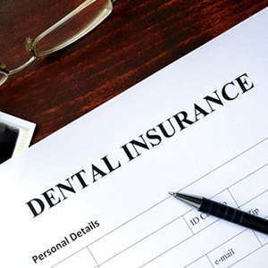 Dental insurance form on table next to X-ray and glasses