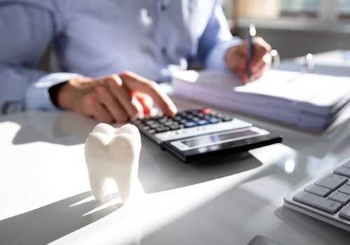 Man at desk, calculating cost of dental treatment