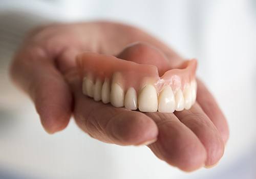 Hand holding a full dentures