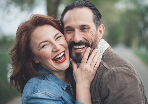 Man and woman showing off beautiful smiles after porcelain veneers