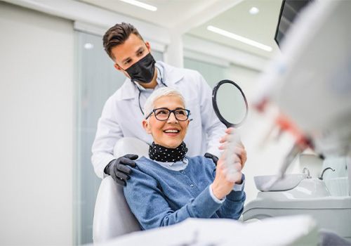 A patient checking her smile with a mirror