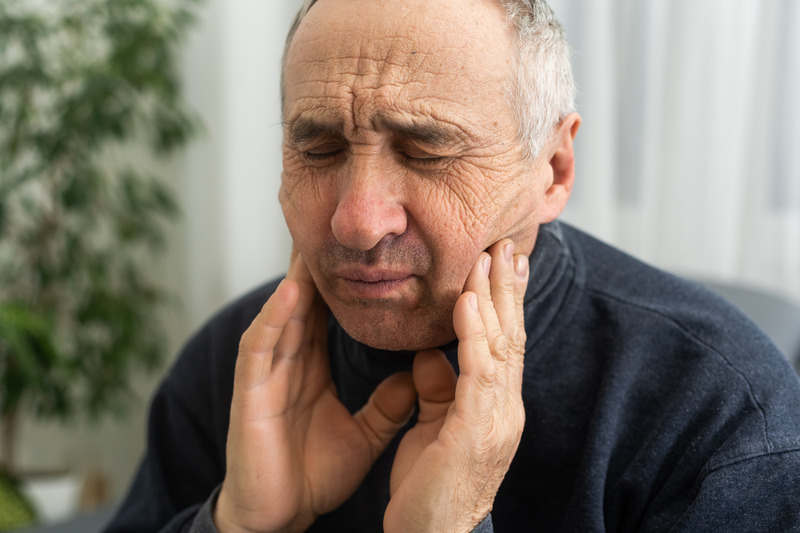 Patient rubbing their cheeks needing wisdom tooth extractions